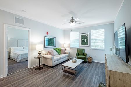 2 BR Apartments In Santa Rosa, FL - The Southern - Living Room Featuring Ceiling Fan And Windows With Pond And Wooded Views